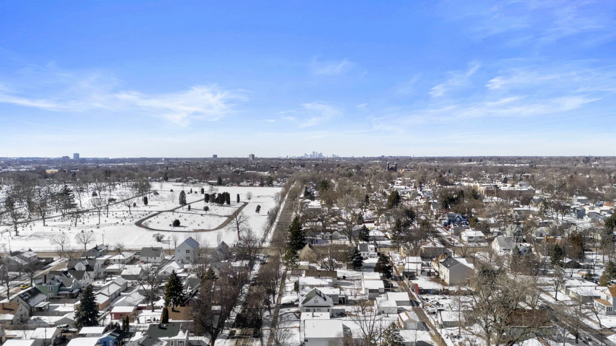 High aerial over the neighborhood with the Minneapolis skyline on the horizon