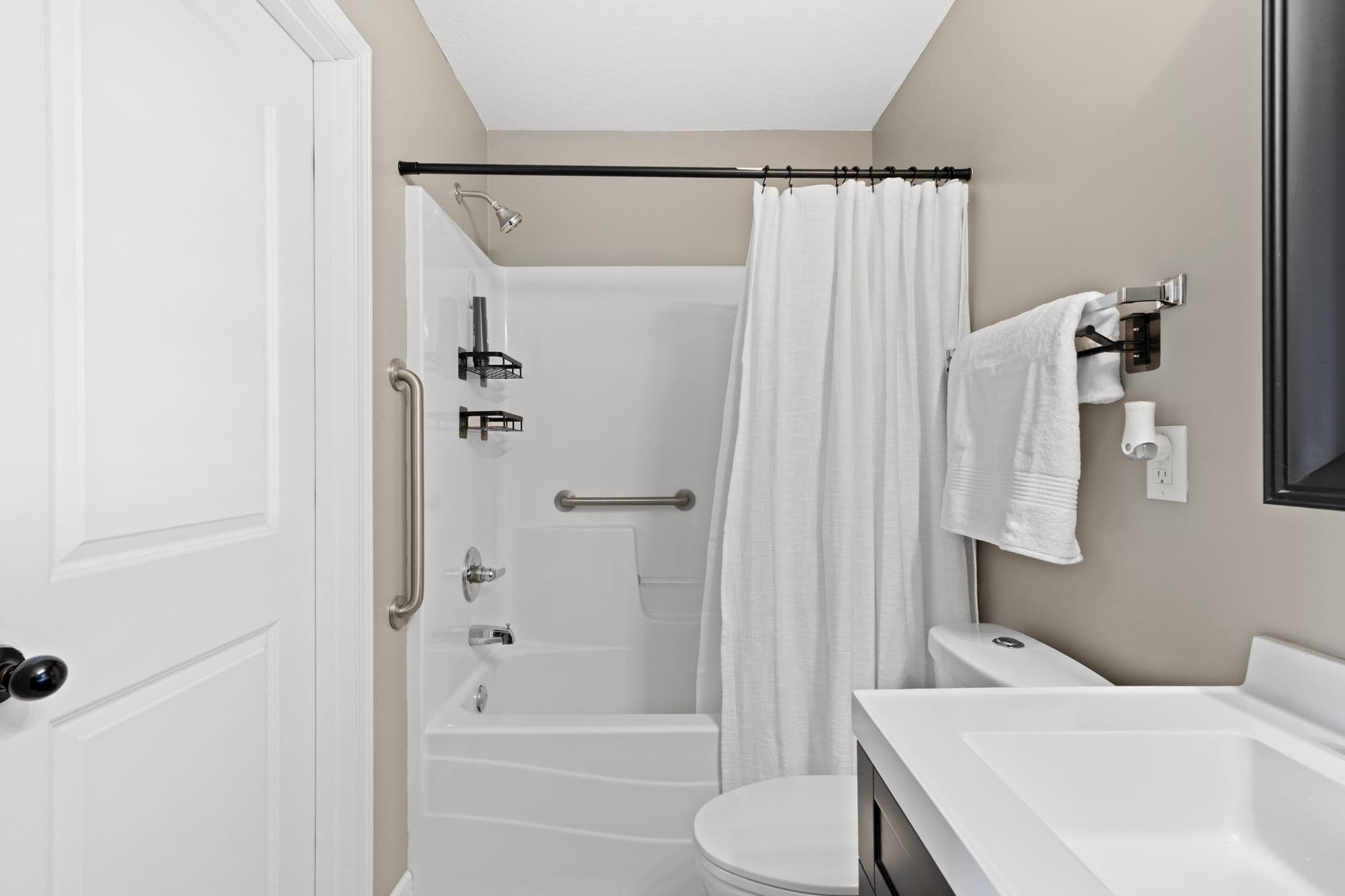Tub-shower with two stainless grab bars and a built-in seat ledge