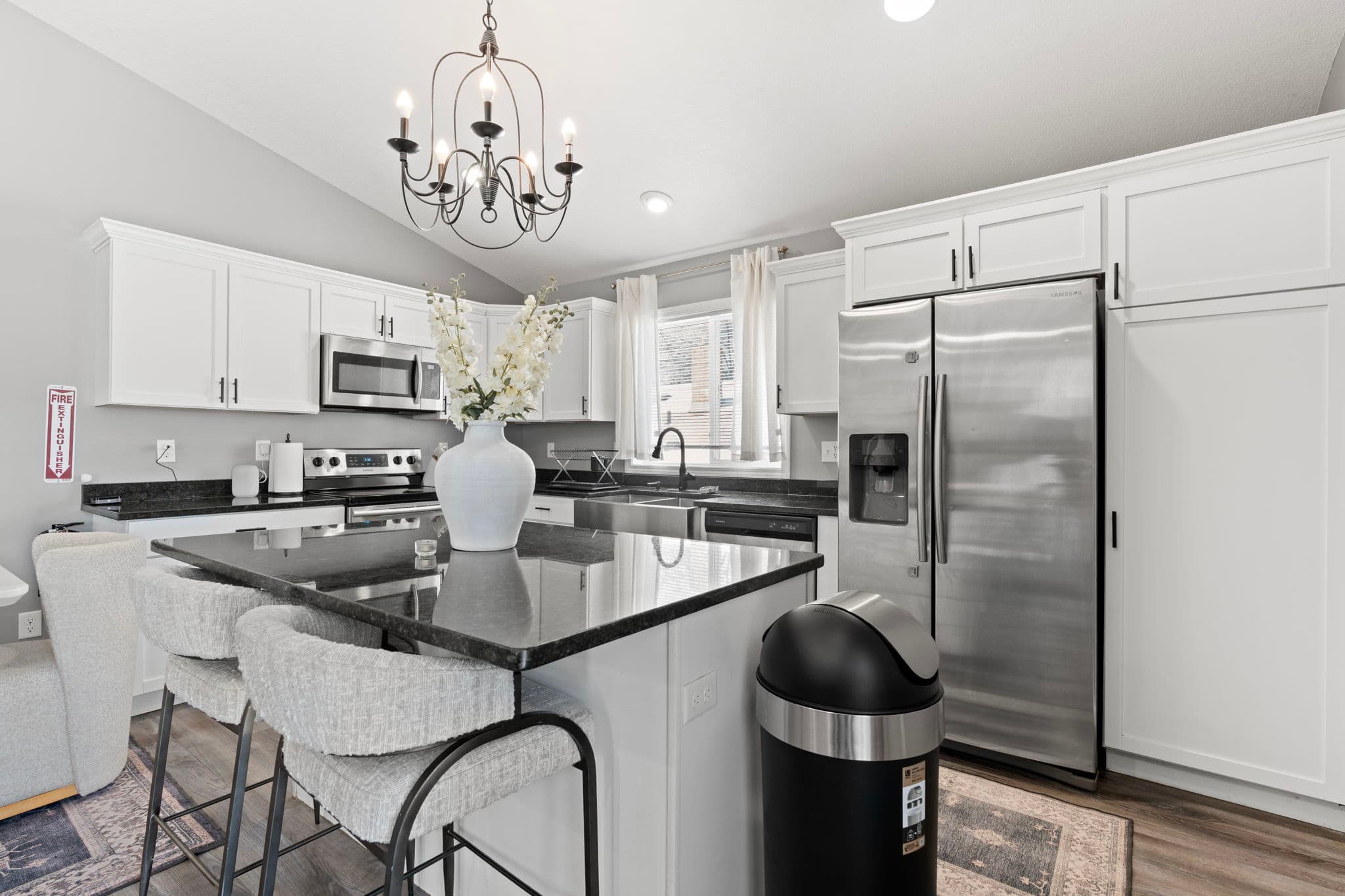 Island seating beneath the chandelier with stainless side-by-side fridge